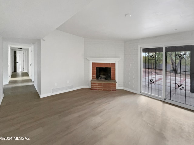 unfurnished living room with dark wood-type flooring and a brick fireplace