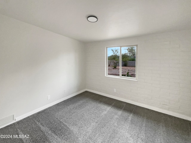 spare room featuring brick wall and carpet flooring