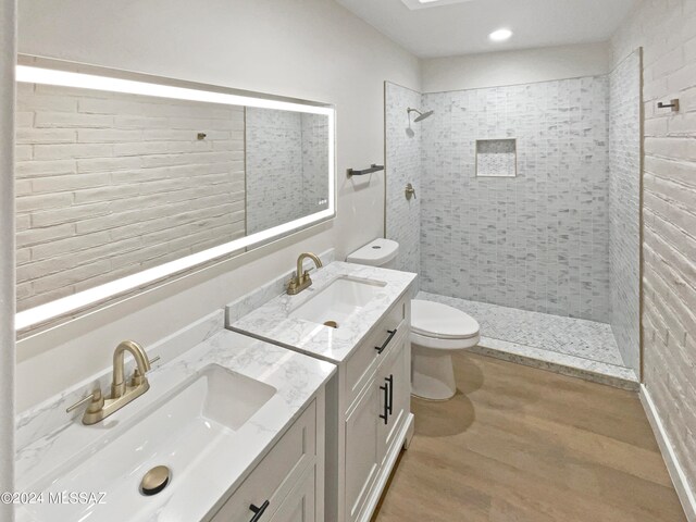 bathroom featuring vanity, toilet, wood-type flooring, and tiled shower