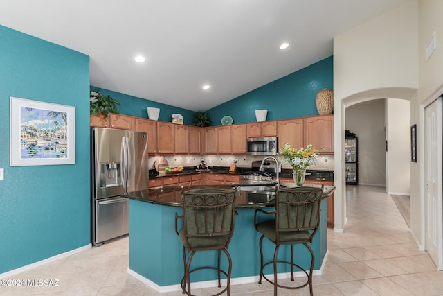 kitchen with tasteful backsplash, appliances with stainless steel finishes, sink, light tile patterned flooring, and a center island with sink