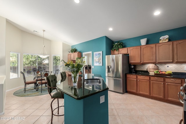 kitchen featuring appliances with stainless steel finishes, sink, lofted ceiling, decorative light fixtures, and a kitchen island with sink