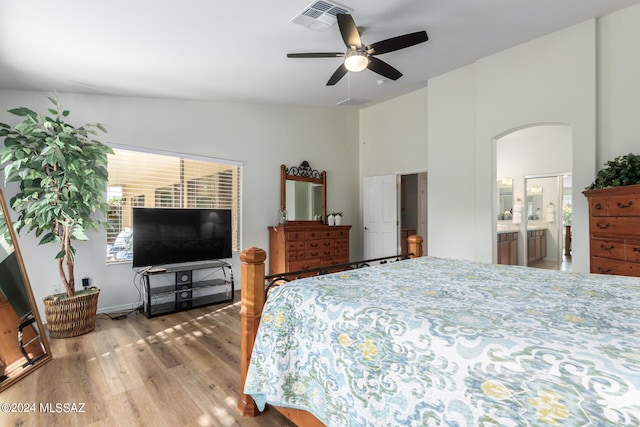 bedroom with connected bathroom, ceiling fan, high vaulted ceiling, and hardwood / wood-style floors