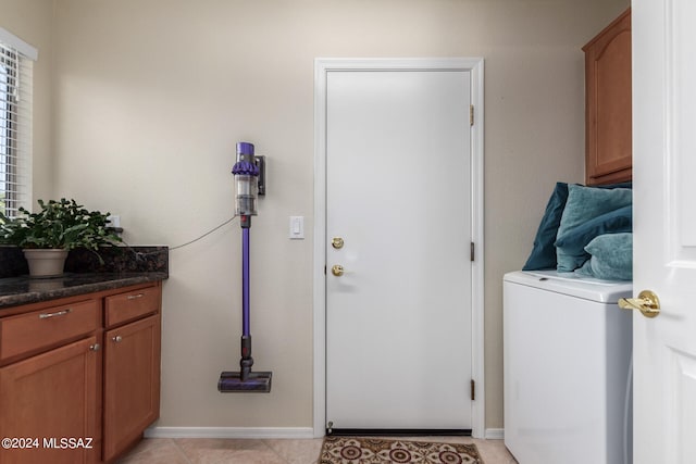 clothes washing area with cabinets and light tile patterned floors