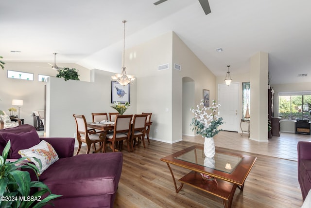 living room featuring vaulted ceiling, light hardwood / wood-style flooring, and ceiling fan with notable chandelier