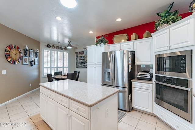 kitchen featuring white cabinets, ceiling fan, stainless steel appliances, and a kitchen island