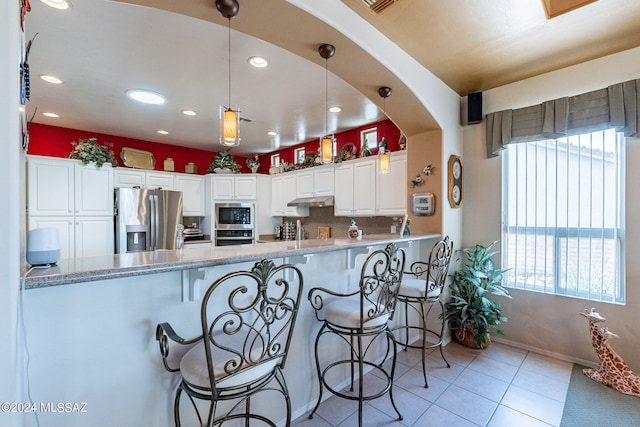 kitchen with white cabinets, decorative light fixtures, stainless steel appliances, and plenty of natural light