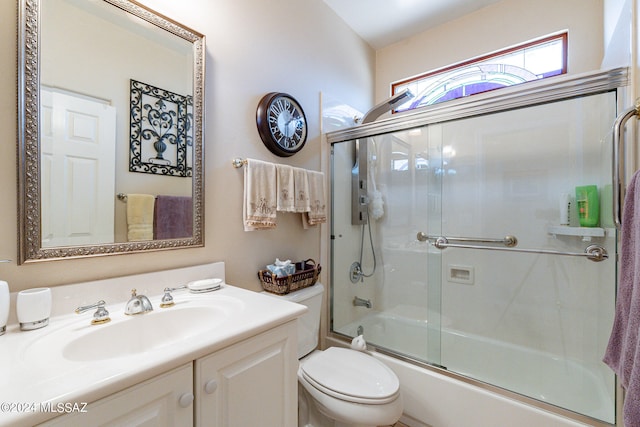 full bathroom featuring vanity, combined bath / shower with glass door, and toilet