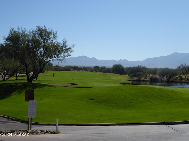 surrounding community with a water and mountain view and a lawn