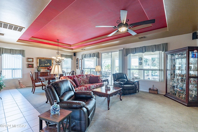 living room featuring light tile patterned flooring, ceiling fan with notable chandelier, and a raised ceiling