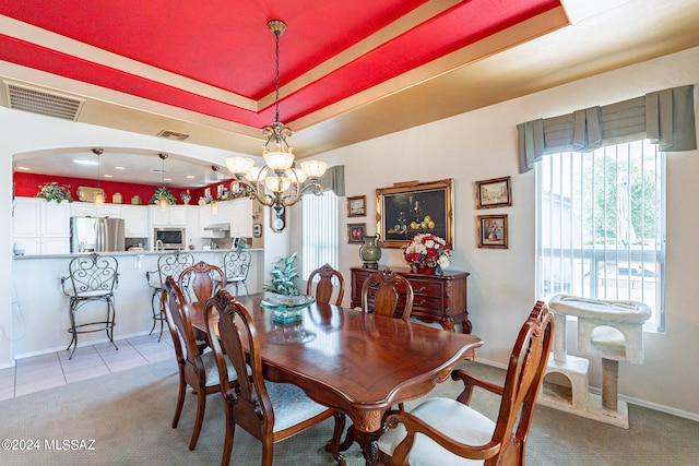 dining space featuring an inviting chandelier, light colored carpet, and a tray ceiling