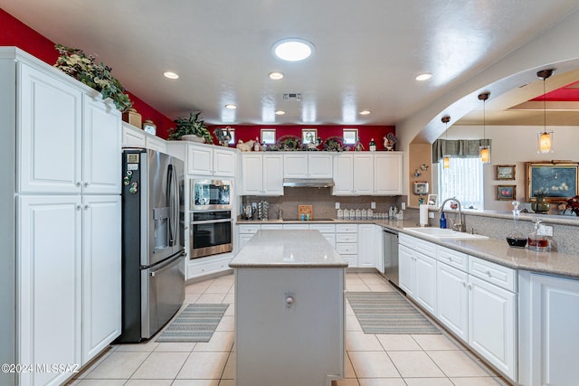 kitchen featuring a kitchen island, sink, white cabinets, appliances with stainless steel finishes, and light stone counters