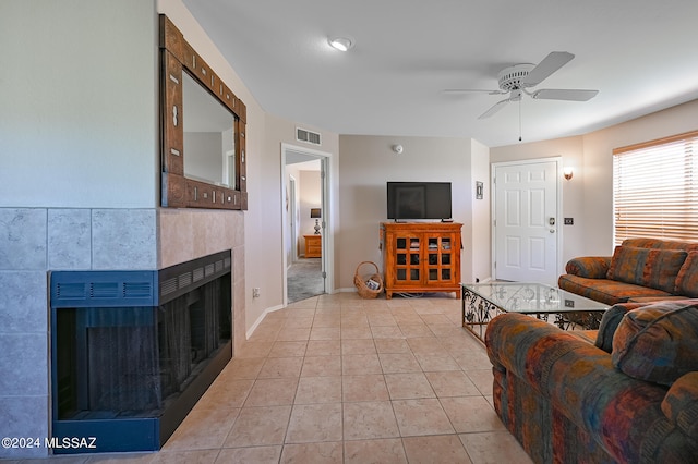 living room featuring tile walls, ceiling fan, light tile floors, and a tiled fireplace