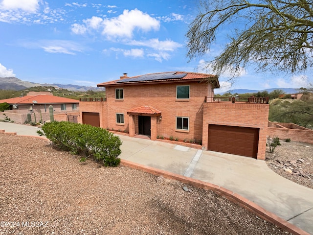 view of front of home with a mountain view, solar panels, and a garage