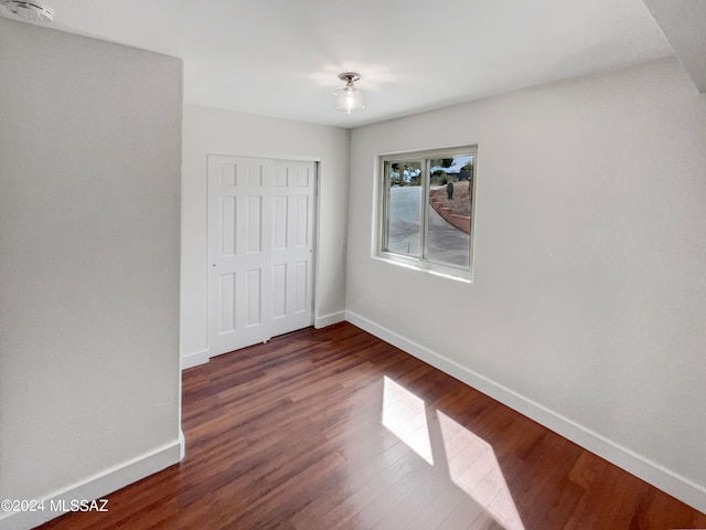 unfurnished bedroom featuring a closet and dark hardwood / wood-style floors