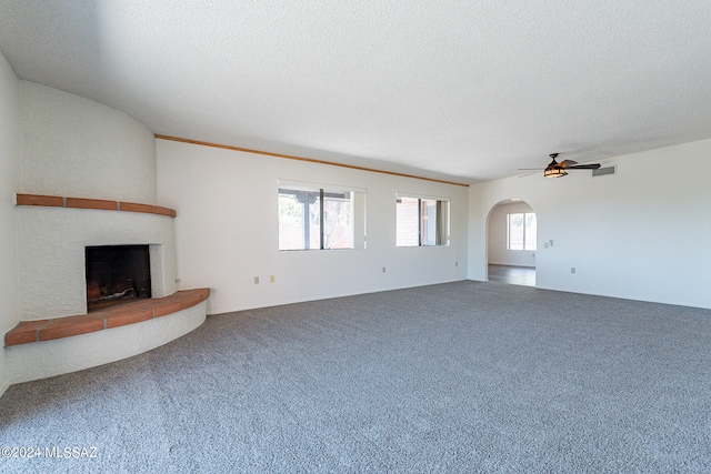 unfurnished living room with carpet flooring, ceiling fan, a textured ceiling, and a fireplace