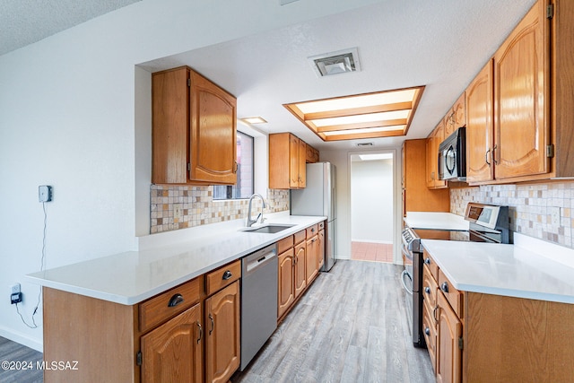 kitchen featuring light hardwood / wood-style floors, appliances with stainless steel finishes, tasteful backsplash, and sink