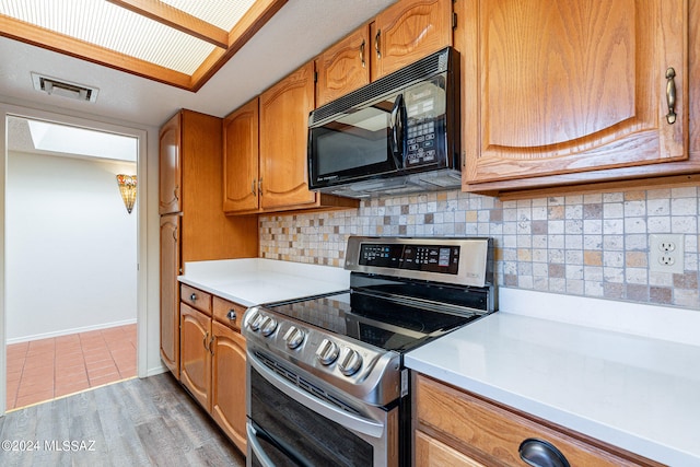 kitchen featuring backsplash, electric range, and light tile floors