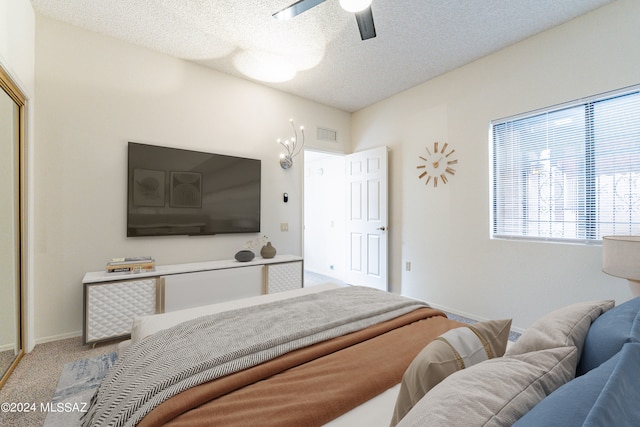 carpeted bedroom with ceiling fan and a textured ceiling