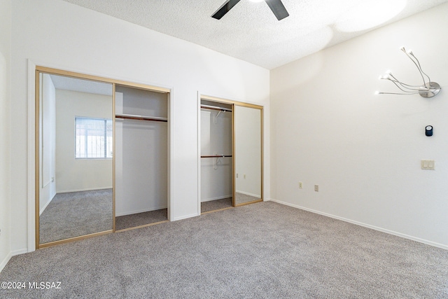 unfurnished bedroom with light colored carpet, two closets, ceiling fan, and a textured ceiling