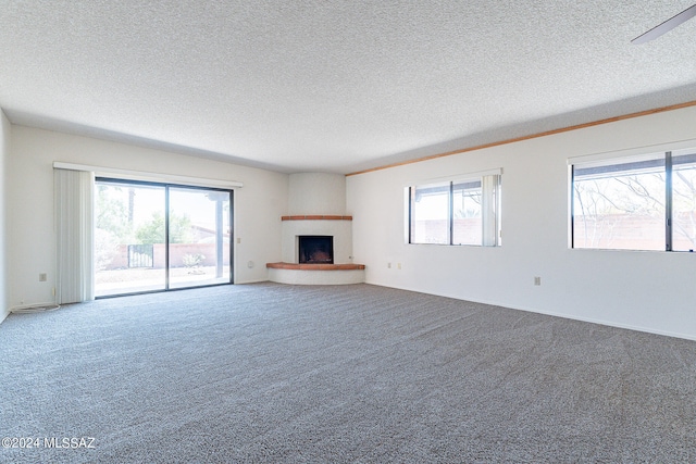 unfurnished living room featuring a healthy amount of sunlight, carpet, and a large fireplace