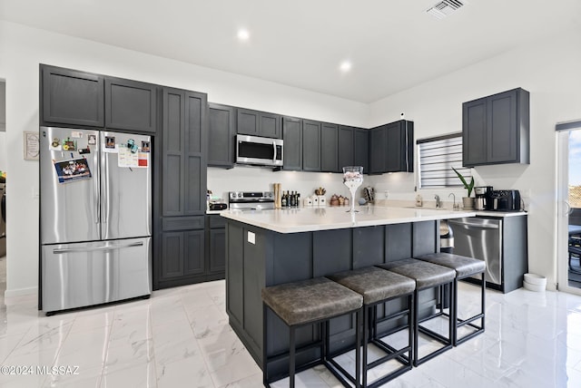 kitchen with a center island, light tile floors, a breakfast bar, sink, and stainless steel appliances