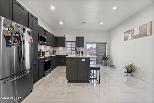 kitchen with appliances with stainless steel finishes, a center island, light tile flooring, and a kitchen bar