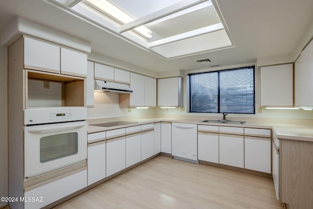 kitchen with sink, white cabinets, light hardwood / wood-style floors, and white appliances