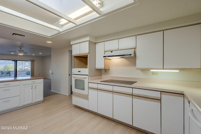 kitchen featuring white cabinets, black electric stovetop, oven, and light hardwood / wood-style floors