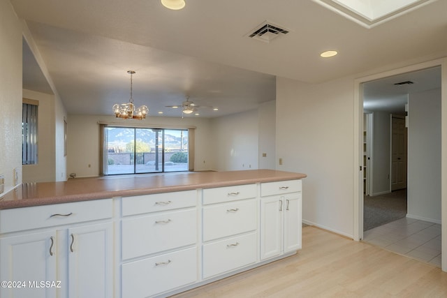 kitchen with ceiling fan with notable chandelier, white cabinets, light hardwood / wood-style floors, and decorative light fixtures