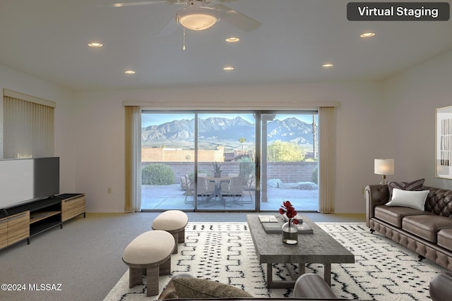 living room featuring a mountain view, ceiling fan, and light carpet