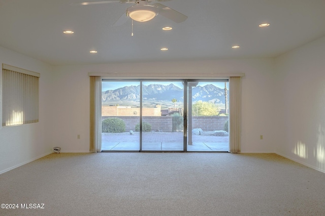 carpeted empty room with a mountain view and ceiling fan