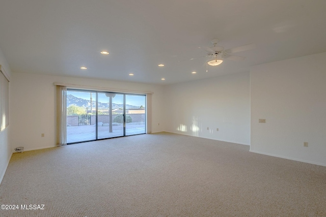 carpeted empty room featuring a mountain view and ceiling fan