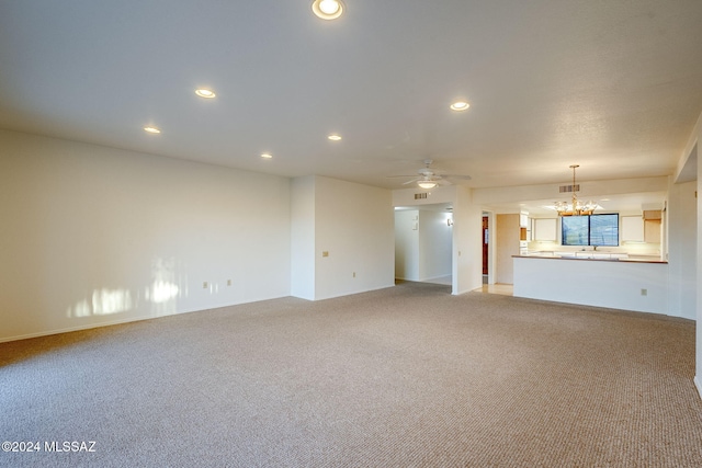 unfurnished living room featuring ceiling fan with notable chandelier and light colored carpet