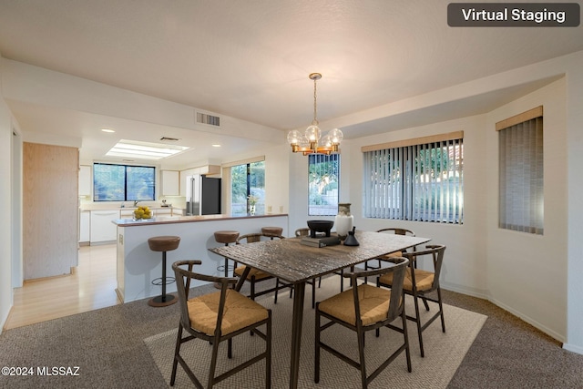 dining room with light colored carpet and a notable chandelier