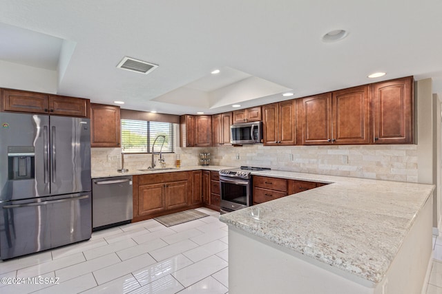 kitchen with tasteful backsplash, appliances with stainless steel finishes, a raised ceiling, sink, and kitchen peninsula