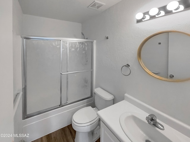 full bathroom with enclosed tub / shower combo, wood-type flooring, vanity, and toilet