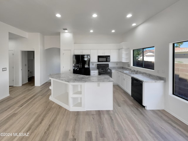 kitchen featuring a center island, white cabinets, black appliances, and light wood-type flooring