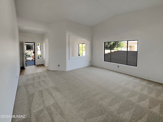 spare room with light carpet and lofted ceiling