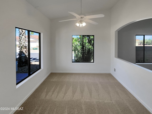 unfurnished room featuring a healthy amount of sunlight, light carpet, ceiling fan, and vaulted ceiling