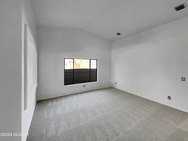 carpeted empty room featuring lofted ceiling