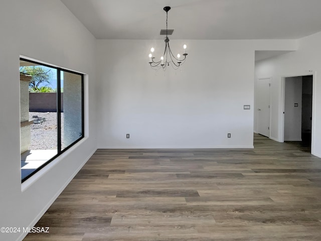 empty room featuring an inviting chandelier and dark hardwood / wood-style flooring