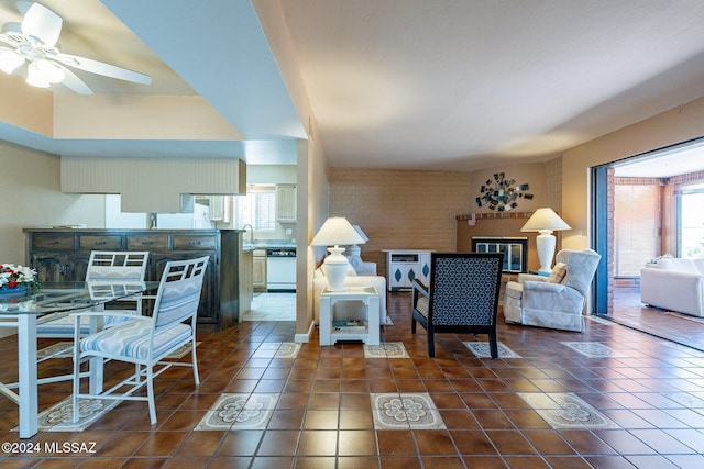 living area with dark tile patterned flooring, a glass covered fireplace, and ceiling fan