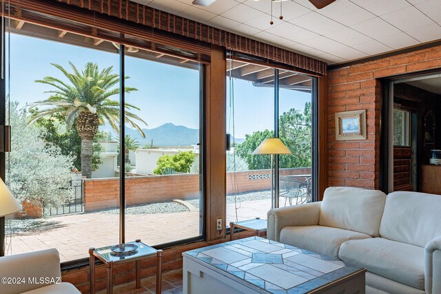 living area featuring brick floor, brick wall, visible vents, and ceiling fan