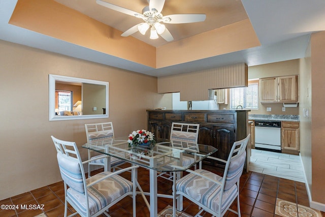 dining space with a tray ceiling, ceiling fan, and tile patterned floors