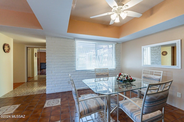 tiled dining space featuring ceiling fan and a raised ceiling