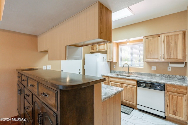 kitchen featuring light brown cabinets, white appliances, a sink, and a center island