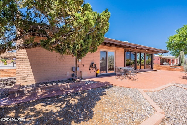 rear view of property with brick siding and a patio