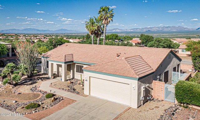 single story home featuring an attached garage, a mountain view, concrete driveway, and stucco siding