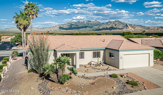 ranch-style house with a garage, concrete driveway, a tile roof, a mountain view, and stucco siding