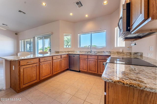 kitchen with light stone counters, stainless steel appliances, visible vents, a sink, and a peninsula